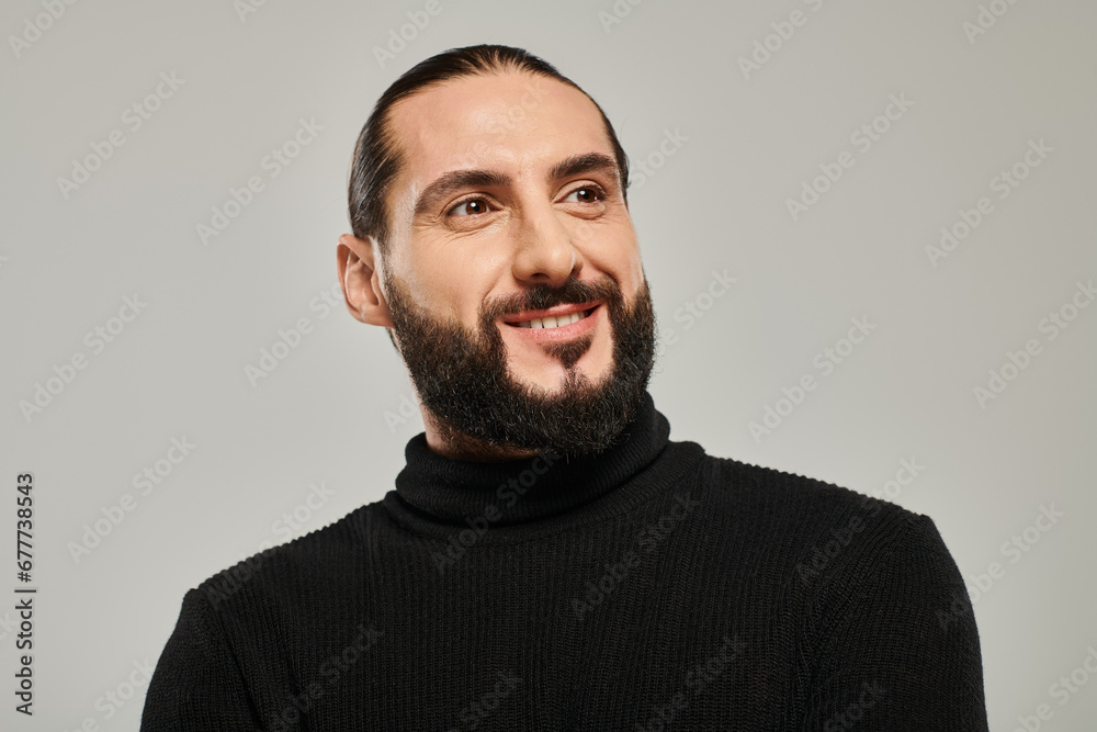 portrait of happy and handsome arabic man with beard posing in black turtleneck on grey backdrop portrait of happy and handsome arabic man with beard posing in black turtleneck on grey backdrop