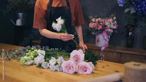 Hands of a female florist choosing flowers for a bouquet at her workplace in a flower shop. Close-up of a florist working. photo