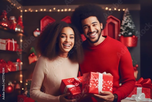 Portrait of young african couple holding wrapped gift presents wear red warm sweaters on christmas eve indoors