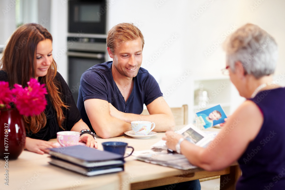 Fototapeta premium Family, photo album and memory with nostalgia, happy and childhood picture at table in living room of home. Mother, man and woman together in lounge with photography to remember and history in house