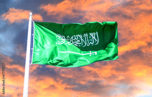 Flag of Saudi Arabia waving in the wind against the sunset sky