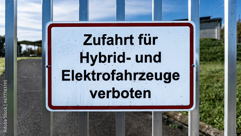 Access is prohibited for hybrid and electric vehicles sign on a fence. Translated from german.