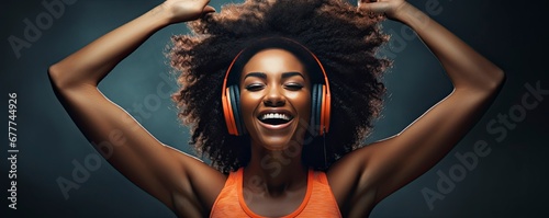 dark skinned woman in good mood, raises arm with muscles, has strong body, dressed in gym outfit, listens audio, Generative AI