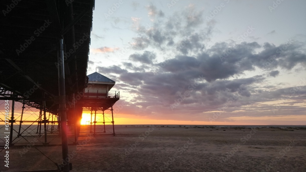 Beautiful sunset scene at a beach with a pier and a lifeguard tower Beautiful sunset scene at a beach with a pier and a lifeguard tower