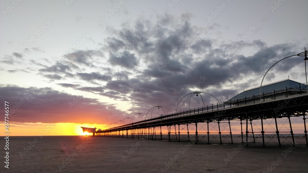 Beautiful view of a sunset and dramatic clouds at a beach with a pier