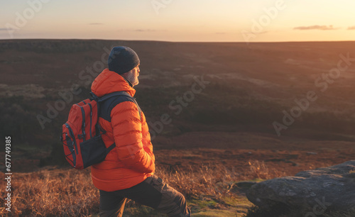 mature man hiking in mountain to take timelaps of sunrise, exercise and fitness for wellness, healthy lifestyle and smile. senior mature gentleman sitting on rock, enjoing calm day photo