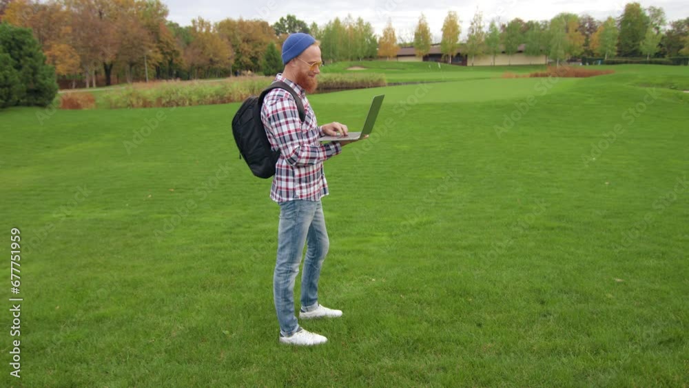 Spectacular autumn landscape with green lawn, distant yellow, orange and red trees. Happy traveller uses laptop for orienting himself in unfamiliar area. High quality 4k footage Spectacular autumn landscape with green lawn, distant yellow, orange and red trees. Happy traveller uses laptop for orienting himself in unfamiliar area. High quality 4k footage