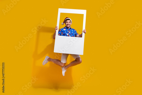 Full body photo of carefree crazy person jumping hold paper album card isolated on yellow color background