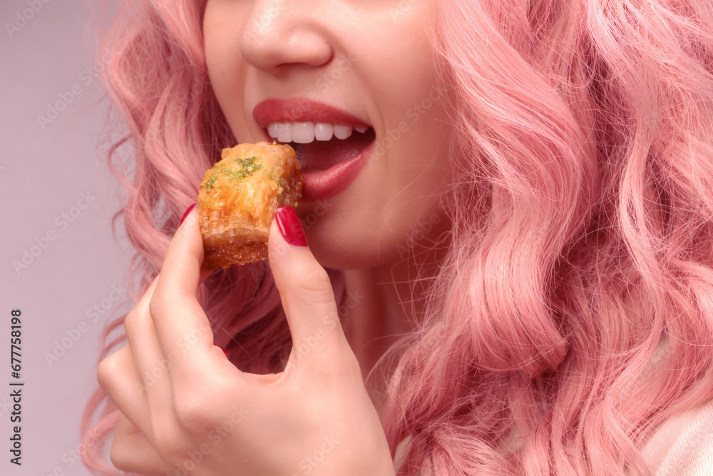 Woman with pink curly hair is eating baklava. Woman with pink curly hair is eating baklava.