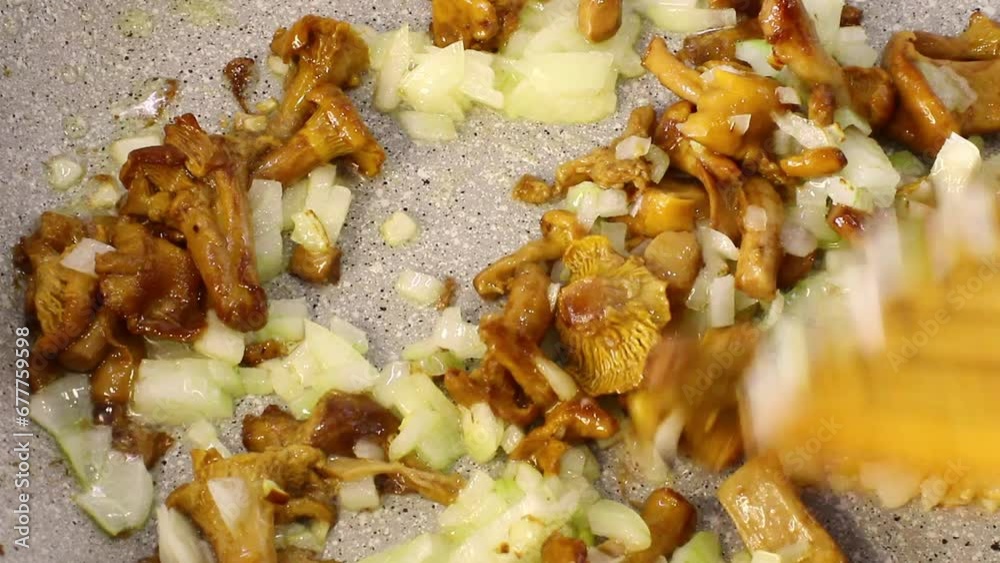 Adding onions to fried mushrooms. Home cooking concept. Mushroom dishes. Chanterelles with onions are fried in oil. Vegetarian food. Close-up. Adding onions to fried mushrooms. Home cooking concept. Mushroom dishes. Chanterelles with onions are fried in oil. Vegetarian food. Close-up.