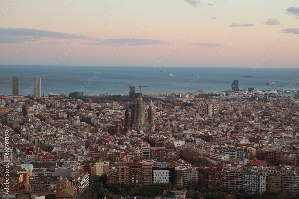 Aerial view of the Barcelona cityscape with a colorful sky in the background