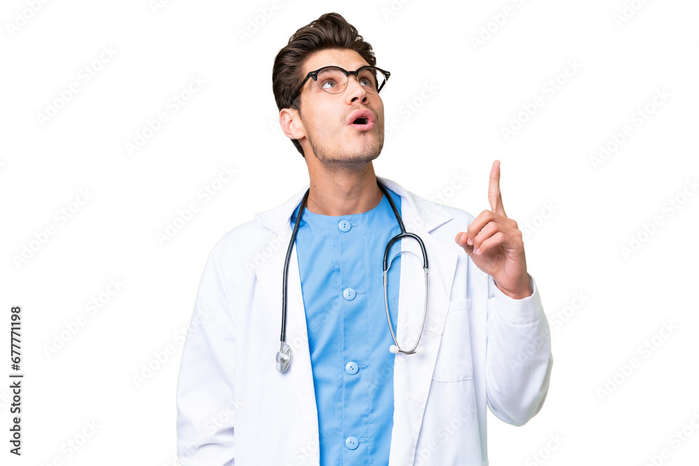 Young doctor man over isolated background pointing up and surprised Young doctor man over isolated background pointing up and surprised