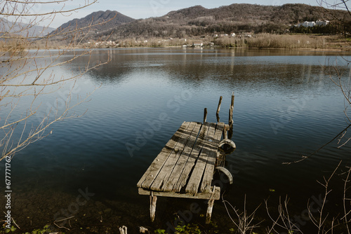 Cinematic landscape. Small jetty in Revine lake, Italy. Mischievous winter atmosphere. Scenic cold light.