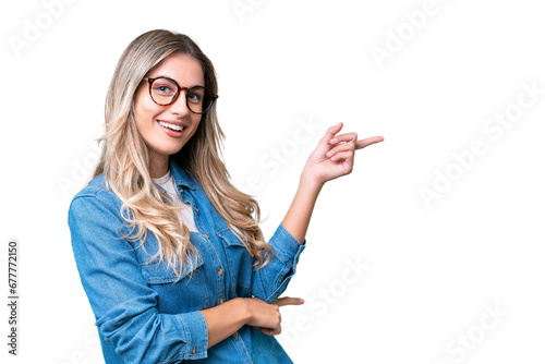 Young Uruguayan woman over isolated background pointing finger to the side