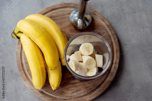 Blender in a top view, with slices of bananas for a banana smoothies. Selective focus on slices of bananas and blurred background.