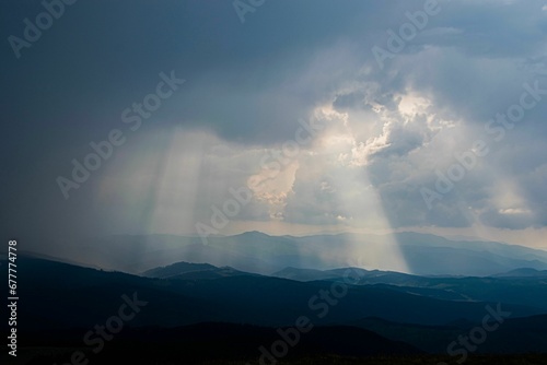 Scenic shot of mountain silhouettes under a cloudy sky with a heavenly effect