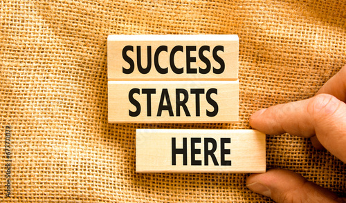 Success starts here symbol. Concept word Success starts here on beautiful wooden block. Businessman hand. Beautiful canvas background. Business motivational success starts here concept. Copy space.