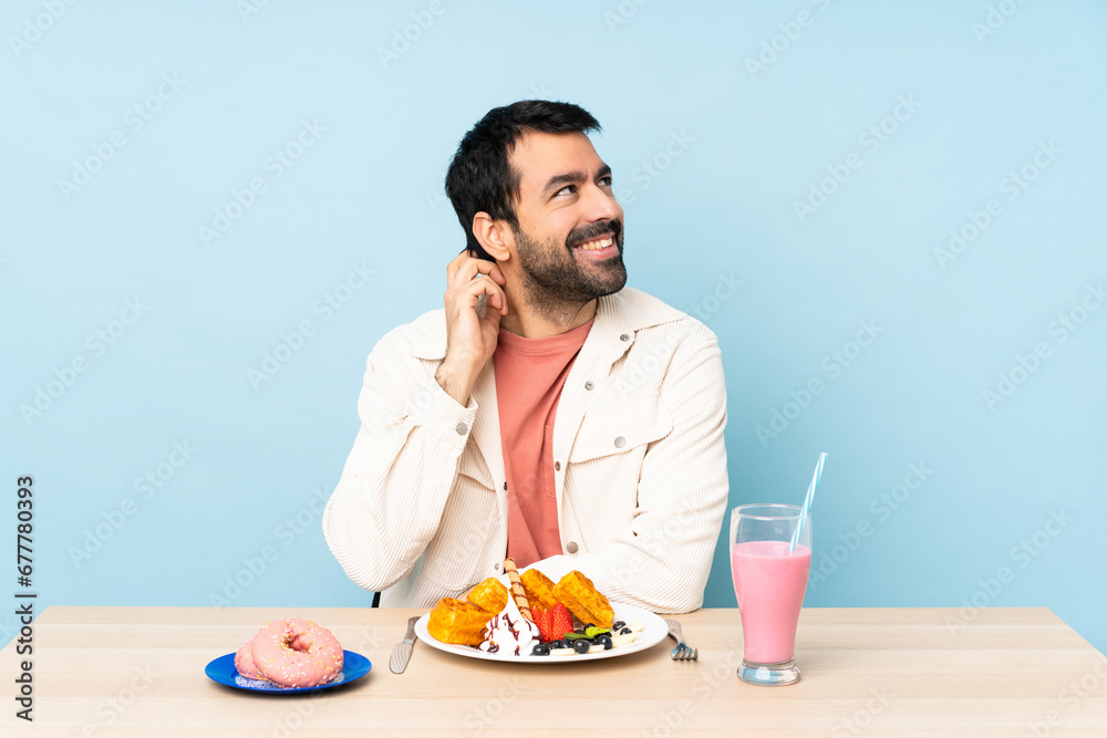 Man at a table having breakfast waffles and a milkshake thinking an idea Man at a table having breakfast waffles and a milkshake thinking an idea