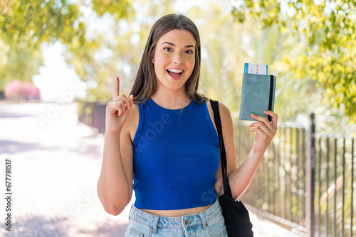 Young pretty Brazilian woman holding a passport at outdoors pointing up a great idea