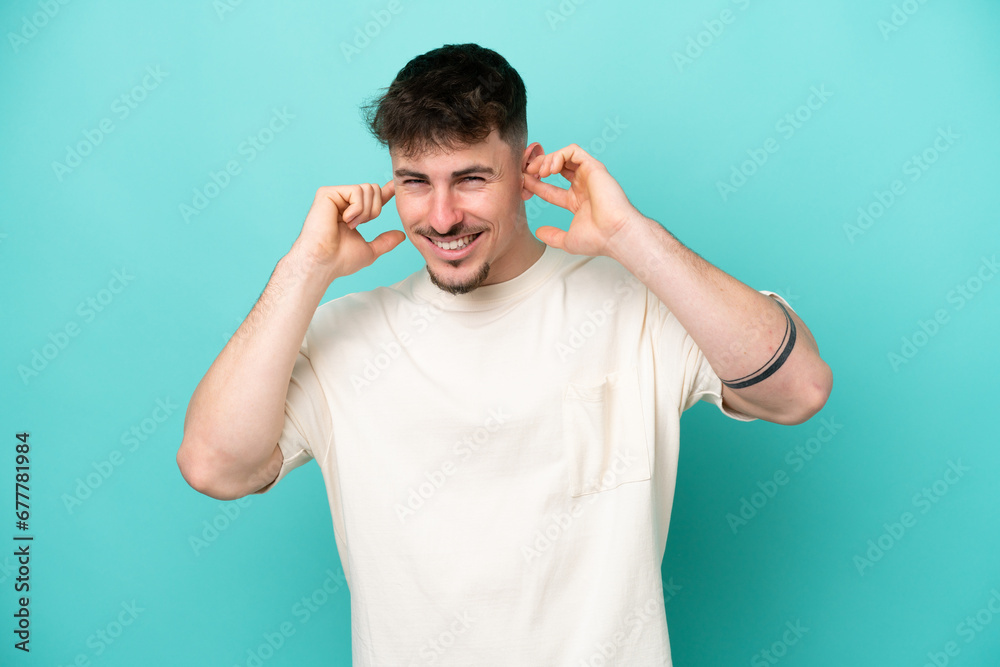 Young caucasian handsome man isolated on blue background frustrated and covering ears Young caucasian handsome man isolated on blue background frustrated and covering ears