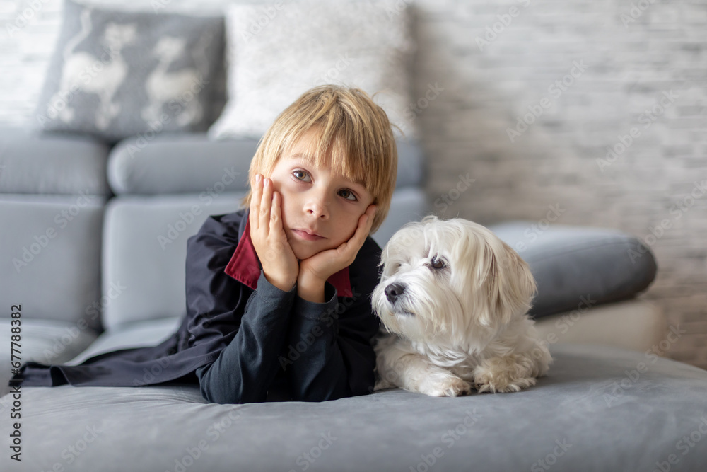 Cutel little child, boy in halloween costume, lying on the couch with pet dog, watching TV Cutel little child, boy in halloween costume, lying on the couch with pet dog, watching TV