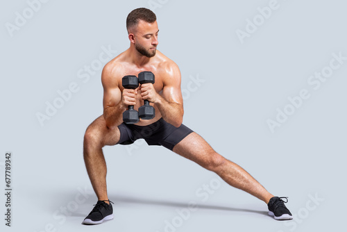 Confident strong muscular millennial european man make exercises with dumbbells for hands  legs