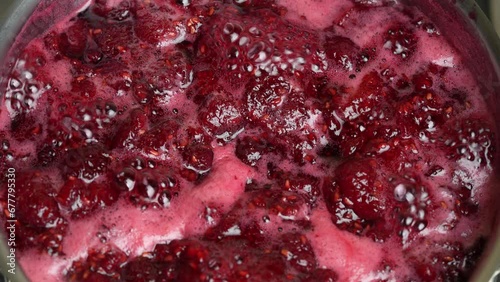 Preparation of freshly picked red raspberries with sugar to make raspberry jam, close up. Cooking homemade raspberry fruit jam in a saucepan. Boiling raspberry fruits for jam photo
