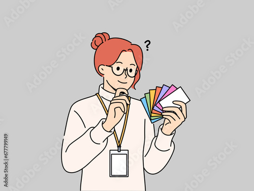 Woman designer holds palette of cards of different colors, choosing desired shade to use in design. Business girl working as designer makes decision on choosing main color for corporate identity