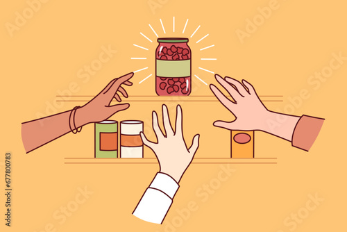 Almost empty shelf in supermarket and hands of people rushing to pick last can of scarce goods. Panicked grocery store customers stock up on scarce merchandise as storm warnings are issued 