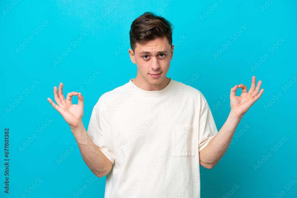 Young handsome Brazilian man isolated on blue background in zen pose Young handsome Brazilian man isolated on blue background in zen pose