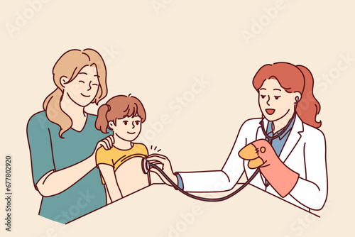 Woman doctor pediatrician applies stethoscope to chest of child sitting on lap of happy mother. Female in white coat works as pediatrician and entertains baby girl during routine examination