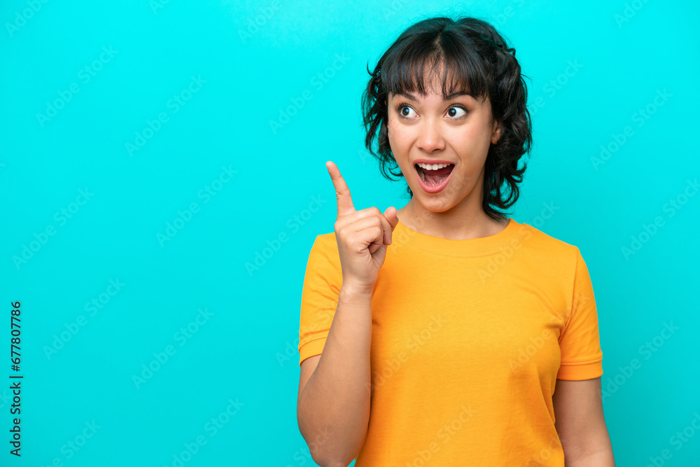 Young Argentinian woman isolated on blue background intending to realizes the solution while lifting a finger up Young Argentinian woman isolated on blue background intending to realizes the solution while lifting a finger up