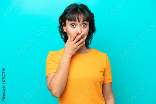 Young Argentinian woman isolated on blue background surprised and shocked while looking right