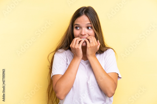 Young caucasian woman isolated on yellow background nervous and scared putting hands to mouth