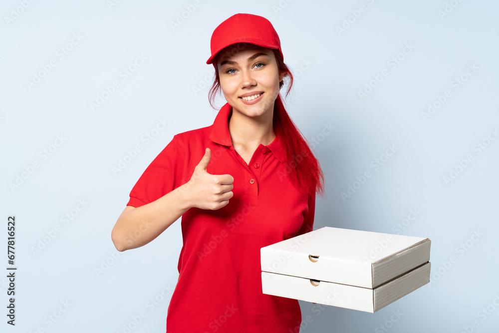 Pizza delivery girl holding a pizza over isolated background giving a thumbs up gesture Pizza delivery girl holding a pizza over isolated background giving a thumbs up gesture