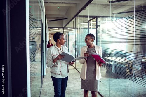 Two Professional Women Engaged in Discussion in a Corporate Environment photo