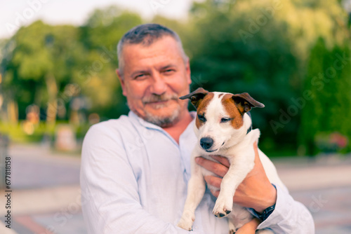 portrait of an adult bearded man holding his little dog of the Jack Russell Terrier breed caring for animals friendship