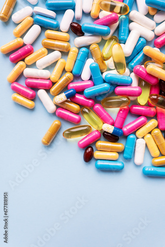 Lots of colorful pills and capsules for different symptoms on a blue background. Health and medicine concept.