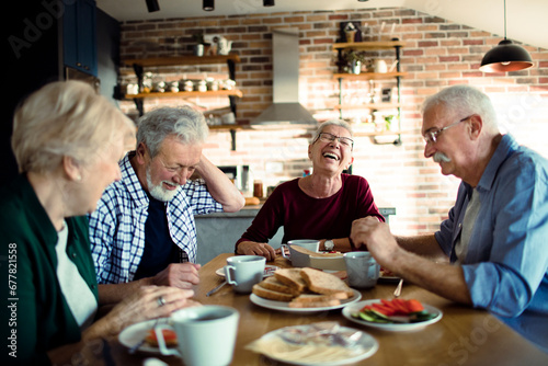 Senior people sitting at dining table together having breakfast