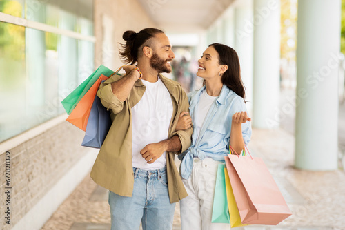 Satisfied millennial caucasian lady and guy shopaholics with many packages