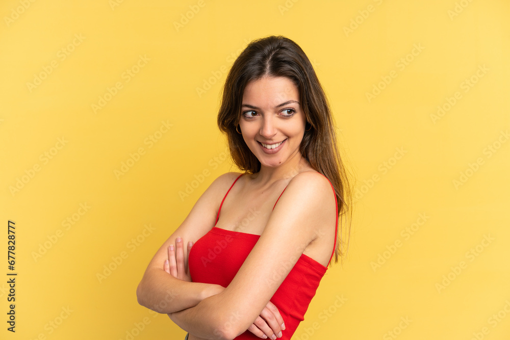 Obraz premium Young caucasian woman isolated on yellow background with arms crossed and happy