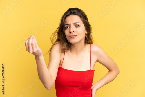 Young caucasian woman isolated on yellow background making Italian gesture