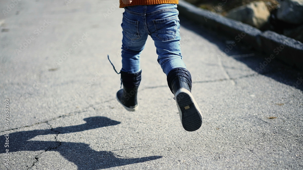Back of carefree young boy running outside wearing yellow pullover and boots during autumn day. Child sprinting, engaged in daily exercise Back of carefree young boy running outside wearing yellow pullover and boots during autumn day. Child sprinting, engaged in daily exercise