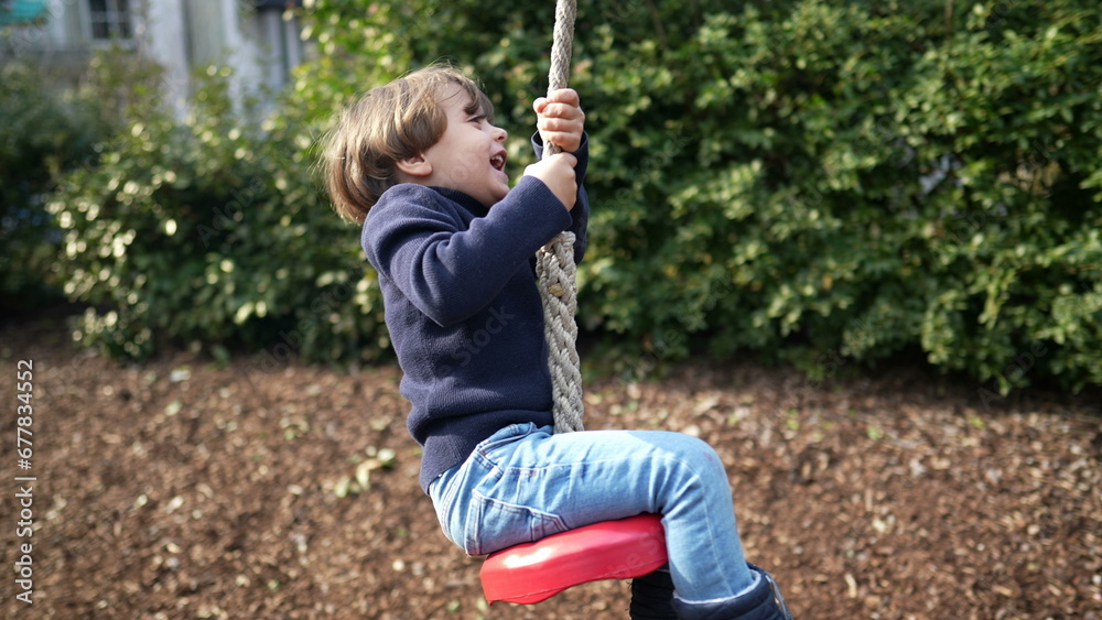 Child having fun at playground park holding into rope and sliding down during autumn fall season. Happy kid enjoying childhood moments Child having fun at playground park holding into rope and sliding down during autumn fall season. Happy kid enjoying childhood moments