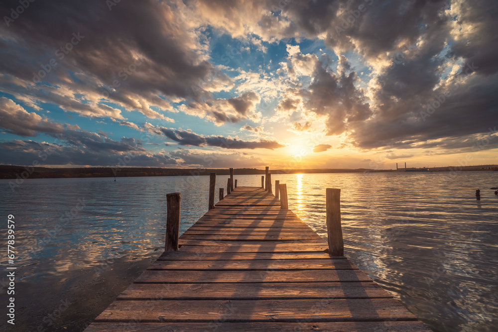 Fototapeta premium Small old fishing Dock at the lake and scenic sunset with dramatic cloudscape over sea