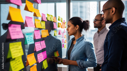A professional team engaged in a brainstorming session, using colorful sticky notes on a glass wall to organize their ideas and strategies. photo