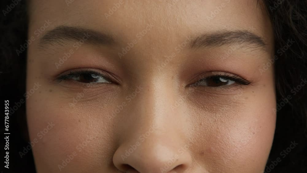 Macro shot of brown black eyes of young beautiful mixed race woman. Slow motion smiling dark brown eyeball iris. Fashion girl looking at camera 4K. Good vision, I see you. Eye is mirror to one's soul Macro shot of brown black eyes of young beautiful mixed race woman. Slow motion smiling dark brown eyeball iris. Fashion girl looking at camera 4K. Good vision, I see you. Eye is mirror to one's soul