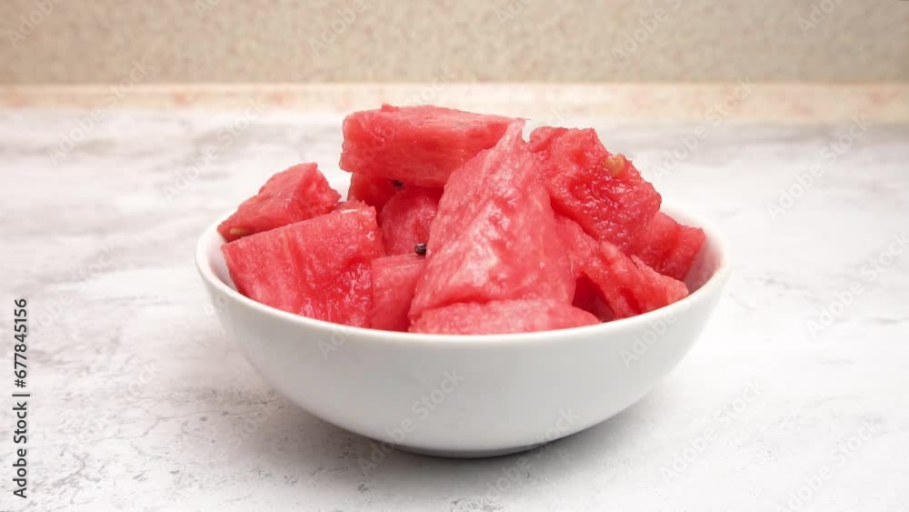 Slices of ripe watermelon in a white bowl against a light background ...