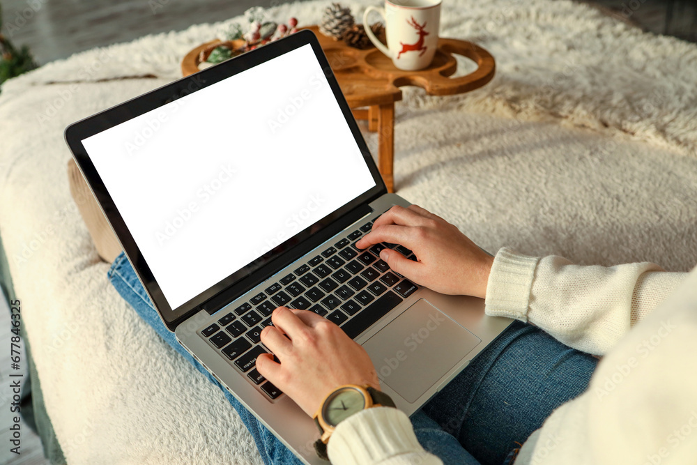 Young woman work on laptop computer with blank display screen with mockup copy space. Modern home living room interior design. Christmas, New Year decorated workspace Young woman work on laptop computer with blank display screen with mockup copy space. Modern home living room interior design. Christmas, New Year decorated workspace