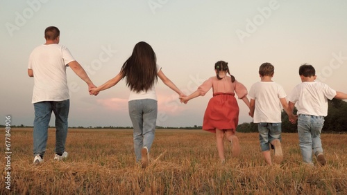 Caring parents and little children run joining hands along field at sunset time © SUPER FOX